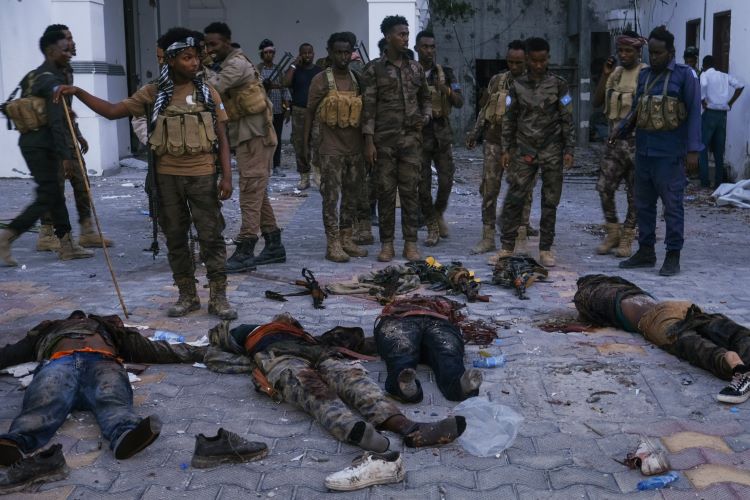 ""جنود صوماليون يقفون قرب جثث عناصر حركة الشباب الذين شنوا هجوم الاحد وسط مقديشو
