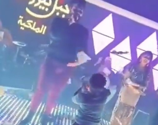 ""طفل الملهى الثاني ينثر النقود عند قدمي المغني المحاط بالراقصات