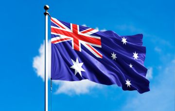 علم أستراليا يرفرف أمام خلفية زرقاء ضبابية من الغيوم.