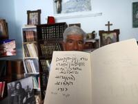 George Zaarour, a specialist in the Aramaic language, a notebook with Aramaic script written on it, in the Syrian mountain village of Maalula, in the Damascus region on May 13, 2019. LOUAI BESHARA / AFP