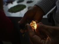 This photo taken on May 17, 2019 shows a buyer inspecting a gemstone at the gems market in Mogok town, north of Mandalay. Burrowing deep underground, thousands of informal miners risk their lives to find gleaming red gems as a law change spurs opportunity in Myanmar's "land of rubies". Ye Aung THU / AFP