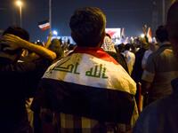 An Iraqi follower of Shiite Muslim cleric Moqtada al-Sadr stands wearing a national flag around his shoulders while demonstrating in the southern city of Basra on May 24, 2019, against involvement in any conflict between Iran and the United States.  Hussein FALEH / AFP