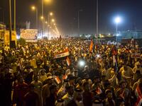 Iraqi followers of Shiite Muslim cleric Moqtada al-Sadr wave national flags and raise protest signs as they demonstrate in the southern city of Basra on May 24, 2019, against involvement in any conflict between Iran and the United States.  Hussein FALEH / AFP