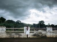 An inhabitant of the roca Agostinho Neto, an abandoned cocoa plantation of Sao Tome and Principe, phones on the paved road of the roca, on May 29, 2019.  Alexis HUGUET / AFP