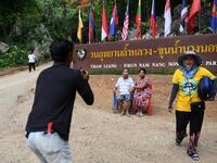 This picture taken on June 13, 2019 shows visitors posing for photos near the entrance of the Tham Luang cave, in which 12 boys from the "Wild Boars" football team and their coach were trapped last year, in the Mae Sai district of Chiang Rai province. Lillian SUWANRUMPHA / AFP