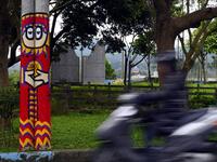 This picture taken on March 30, 2019 shows an motorcyclist riding past a utility pole painted by Hakka graffiti artist Wu Tsun-hsien in the Taiwanese village of Ruan Chiao. Nestled in the mist-covered foothills of Taiwan's central mountain range, Ruan Chiao village is virtually devoid of young people, but artist Wu Tsun-hsien is coaxing the Instagram generation back by transforming local homes into a canvas of colour. Sam YEH / AFP