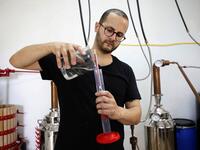 Palestinian distiller Nader Muaddi uses an alcoholometer to measure the amount of alcohol in his Arak in the West Bank village of Beit Jala, near Bethlehem, on June 16, 2019. In his basement, distiller Muaddi made fewer than 500 bottles of liquor last year, but it is earning global acclaim and reviving interest in the Palestinian alcohol sector. On the outskirts of the city famed for Jesus's birth, the 35-year-old illustrates the handcrafted way he makes Arak, an anise-flavoured drink popular in the Middle 