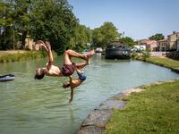 Young men dive into the Canal du Midi at the Port du Segala in Labastide d'Anjou on July 23, 2019 as a new heatwave blasted into northern Europe that could set records in several countries. ERIC CABANIS / AFP