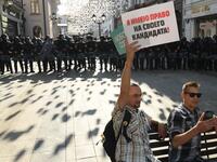 A protester holding a placard reading "I have the right on my candidate" sits on a bench in front of a line of riot police during an unauthorised rally demanding independent and opposition candidates be allowed to run for office in local election in September, in downtown Moscow on July 27, 2019.  Kirill KUDRYAVTSEV / AFP