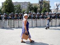 A woman walks past servicemen of the Russian National Guard during an unauthorised rally demanding independent and opposition candidates be allowed to run for office in local election in September, in downtown Moscow on July 27, 2019.  Maxim ZMEYEV / AFP