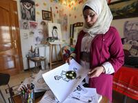 Syrian Cartoonist Amani al-Ali shows one of drawings, depicting a naked President Bashar al-Assad covering his lower torso with a chemical weapons hazard symbol, at her home studio in the city of Idlib in the eponymous northwestern province Omar HAJ KADOUR / AFP