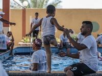 A trainer helps a Palestinian amputee child during a summer camp origanized by the Palestinian Children's Relief Fund (PCRF) in the town of Khan Yunis in the southern Gaza strip on August 3, 2019.  SAID KHATIB / AFP