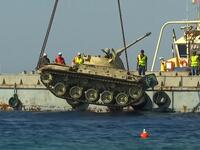 The crane lowers a Jordanian Armed Forces' armoured vehicle. (YouTube Screenshot)