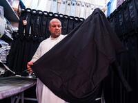A man showcases a black garb in a shop lined-up with black and other coloured shirts, to be sold to Shiite Muslim pilgrims amidst preparations ahead of the Shiite religious mourning period of Ashura in the central Iraqi holy shrine city of Najaf on August 31, 2019.  Haidar HAMDANI / AFP