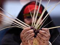 An Emirati woman knits together straw leaves in a display of traditional crafts on the first day of the Abu Dhabi International Hunting and Equestrian exhibition (ADIHEX) in the UAE capital on August 31, 2019.  KARIM SAHIB / AF