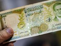 A merchant holds a Syrian pound note, bearing a portrait of late Syrian President Hafez al-Assad, at a market in the Kurdish-majority city of Qamishli in northeast Syria.  Delil SOULEIMAN / AFP