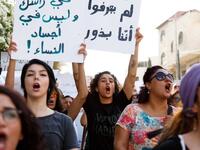Arabic slogans on placards call for an end to violence against women and introducing a law for family protection against domestic violence."  (Twitter)