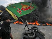 An Iraqi protester waves an Iraqi Hezbollah flag during a demonstration against state corruption, failing public services and unemployment in the Baladiyat district of the capital Baghdad on October 2, 2019. Iraq's president and the United Nations urged security forces to show restraint after two protesters were killed in clashes with police that other top officials blamed on "infiltrators." AHMAD AL-RUBAYE / AFP