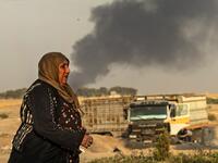 A woman walks as smoke billows following Turkish bombardment in Syria's northeastern town of Ras al-Ain in the Hasakeh province along the Turkish border on October 9, 2019. Turkey launched an assault on Kurdish forces in northern Syria with air strikes and explosions reported along the border. President Recep Tayyip Erdogan announced the start of the attack on Twitter, labelling it "Operation Peace Spring".  Delil SOULEIMAN / AFP