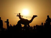 A Palestinian jockey is silhouetted as he competes in a local camel race held at the destroyed Gaza airport, in Rafah in the southern Gaza Strip on October 20, 2019. SAID KHATIB / AFP
