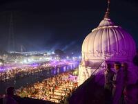 Indian security personnel keep watch as Hindu devotees light earthen lamps on the banks of the River Sarayu on the eve of "Diwali" festival during an event organised by the Uttar Pradesh government, in Ayodhya on October 26, 2019. "Diwali", the Festival of Lights, marks victory over evil and commemorates the time when Hindu god Lord Rama achieved victory over Ravana and returned to his kingdom Ayodhya. SANJAY KANOJIA / AFP