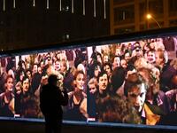 A spectators stands in front of a 3D video installation projected on the so-called East Side Gallery, a 1,3 km-long portion of the Berlin wall, during a rehearsal on November 3, 2019 in Berlin.  Tobias SCHWARZ / AFP