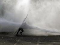 A demonstrator is hit by a riot police water cannon spray during a protest against the government in Santiago on November 18, 2019. President Sebastian Pinera condemned on Sunday for the first time what he called abuses committed by police in dealing with four weeks of violent unrest that have rocked Chile and which has left 22 people dead and more than 2,000 injured. Chileans have been protesting social and economic inequality, and against an entrenched political elite that comes from a small number of the