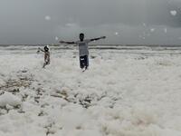 Residents play over foamy discharge, caused by pollutants, as it mixes with the surf at Marina beach in Chennai on December 1, 2019. Arun SANKAR / AFP