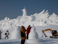 Tourist pose in front of an ice sculpture ahead of the opening of the Harbin International Ice and Snow Festival in Harbin, in China's northeast Heilongjiang province on January 4, 2020. NOEL CELIS / AFP
