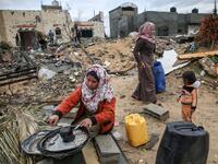 A Palestinian woman carries washes the dishes outside her shack in Khan Yunis in the southern Gaza Strip on January 10, 2020. A family of 17, whose house was destroyed by an Israeli air strike last November, now live in a shack in cold weather and heavy rain. SAID KHATIB / AFP