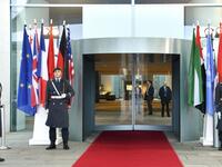 Guards stand next to the flags of the participating countries at the entrance of the German Chancellery in Berlin on January 19, 2020. AFP/ File
