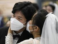 A couple wearing protective face masks attend a mass wedding ceremony organised by the Unification Church at Cheongshim Peace World Center in Gapyeong on February 7, 2020. South Korea has confirmed 24 cases of the SARS-like virus so far and placed nearly 260 people in quarantine for detailed checks amid growing public alarm. Jung Yeon-je / AFP