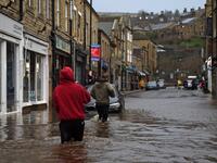 People wade through floodwater in the streets of Hebden Bridge, northern England, on February 9, 2020, as Storm Ciara swept over the country. Britain and Ireland hunkered down Sunday for a powerful storm expected to disrupt air, rail and sea links, cancel sports events, cut electrical power and damage property. With howling winds and driving rain, forecasters said Ciara would also hit France, Belgium, the Netherlands, Switzerland and Germany. Oli SCARFF / AFP