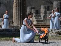 A woman dressed as a priestess lits the Olympic flame during the Olympic ceremony in ancient Olympia, ahead of Tokyo 2020 Olympic Games on March 12, 2020. ARIS MESSINIS / AFP