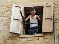 A Lebanese boy smiles as he looks out of a window during confinement at home due to the COVID-19 pandemic, in the historic part of the southern coastal city of Sidon (Saida), on April 6, 2020. Lebanon's President called on international donors to provide financial assistance to the crisis-hit country as it grapples with a severe economic downturn compounded by the novel coronavirus pandemic. JOSEPH EID / AFP