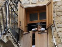 A Lebanese girl looks out of a window during confinement at home due to the COVID-19 pandemic, in the historic part of the southern coastal city of Sidon (Saida), on April 6, 2020. Lebanon's President called on international donors to provide financial assistance to the crisis-hit country as it grapples with a severe economic downturn compounded by the novel coronavirus pandemic. JOSEPH EID / AFP