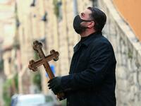A Christian pilgrim wearing protective gear amid the COVID-19 outbreak, prays at the first station while making his way alone in the Procession of the Way of the Cross along the Via Dolorosa, to mark Good Friday in Jerusalem on April 10, 2020. All cultural sites in the Holy Land are shuttered, regardless of their religious affiliation, as authorities seek to forestall the spread of the deadly respiratory disease, which will prevent Christians from congregating for the Easter service, this coming Sunday for 