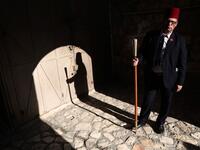 The Kawas of the Franciscan order waits for a priest by the entrance of the yard of the Church of the holy Sepulchre in Jerusalem's Old City on April 9, 2020, amid the COVID-19 pandemic. All cultural sites in the Holy Land are shuttered, regardless of their religious affiliation, as authorities seek to forestall the spread of the deadly respiratory disease, which will prevent Christians from congregating for the Easter service, this coming Sunday for Catholic worshippers, then a week later on April 19 for O