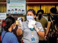 An employee wearing a face mask amid fears of the spread of COVID-19 coronavirus checks the temperature of a customer outside a gold shop in Bangkok's Chinatown on April 15, 2020. Hundreds of Bangkok residents rushed to goldsmith shops in order to sell their jewelries as gold prices reached its highest levels since 2012. Mladen ANTONOV / AFP
