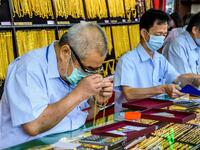 An employee checks a gold chain offered for sale in a gold shop in Bangkok's Chinatown on April 15, 2020. Hundreds of Bangkok residents rushed to goldsmith shops in order to sell their jewelries as gold prices reached its highest levels since 2012. Mladen ANTONOV / AFP