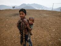 This photo taken on February 9, 2020 shows a boy carrying his brother in front of their house in Karmawlawyi village in Myanmar's Sagaing region, near the border with India. The king of the Konyak tribe sleeps in Myanmar, but eats in India -- his house, village and people divided by a mountain border which serves as a vulnerable lifeline now severed by a coronavirus lockdown.  Ye Aung THU / AFP