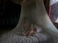 Satere-Mawe indigenous mother Priscila Tavares Batista, 36 remains in a bed protected by a mosquito net with her son Jone Tavares, 2, after being treated with medicinal herbs after showing symptoms of COVID-19, in the Wakiru community, in Taruma neighbourhood, a rural area west of Manaus, Amazonas State, Brazil, on May 17, 2020, during the novel coronavirus pandemic.Ricardo OLIVEIRA / AFP