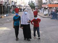 A Palestinian woman and paper-hat-clad children, wearing masks due to the COVID-19 coronavirus pandemic, walk along a street in Gaza City early on May 24, 2020, after performing prayers on the first day of Eid al-Fitr, the Muslim holiday which starts at the conclusion of the holy fasting month of Ramadan. Local authorities in the Hamas-run Palestinian enclave allowed mosques to reopen for Eid al-Fitr as social distancing procedures for the novel coronavirus are maintained while encouraging the elderly to pe