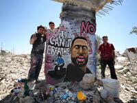 Syrian artists Aziz Asmar and Anis Hamdoun finish a mural depicting George Floyd, an unarmed African-American man who died while while being arrested and pinned to the ground by the knee of a Minneapolis police officer, in the town of Binnish in Syria's northwestern Idlib province on June 1, 2020. OMAR HAJ KADOUR / AFP