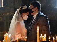 A bride and a bridegroom wearing protective face masks exchange kisses during a wedding ceremony in a church in the Saghmosavan village outside Yerevan on June 14, 2020, as the country tries to curb the spread of the COVID-19, the disease caused by the novel coronavirus. Karen MINASYAN / AFP
