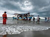Fishermen helping Rohingya onto the beach at Lancok village in North Aceh Regency. AFP