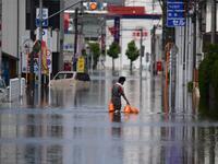 A worker wades through flood waters as he delivers gas bottles in Kurume, in Fukuoka Prefecture on July 8, 2020. Japan will deploy more troops to search for survivors of devastating floods and landslides that have killed at least 52 people in the southwest of the country, Prime Minister Shinzo Abe pledged CHARLY TRIBALLEAU / AFP
