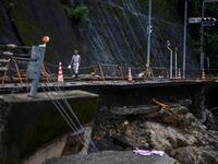 A man walks along a road damaged from recent heavy rains and flooding in the village of Kuma, Kumamoto prefecture on July 9, 2020. Japanese emergency services and troops were scrambling on July 9 to reach thousands of homes cut off by catastrophic flooding and landslides that have killed dozens and caused widespread damage. CHARLY TRIBALLEAU / AFP