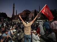 A man flashes the V for Victory hand sign and waves a flag outside the Hagia Sophia museum in Istanbul on July 10, 2020 as people gather to celebrate after a top Turkish court revoked the sixth-century Hagia Sophia's status as a museum, clearing the way for it to be turned back into a mosque. The Council of State, the country's highest administrative court which on July 2 debated a case brought by a Turkish NGO, cancelled a 1934 cabinet decision and ruled the UNESCO World Heritage site would be reopened to 