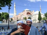Two men take a selfie picture in front of Hagia Sophia on July 11, 2020 in Istanbul, a day after a top Turkish court revoked the sixth-century Hagia Sophia's status as a museum, clearing the way for it to be turned back into a mosque. The World Council of Churches, which represents 350 Christian churches, said on July 11 it wrote to Turkey's President expressing "grief and dismay" over his decision to turn the Hagia Sophia back into a mosque. Ozan KOSE / AFP